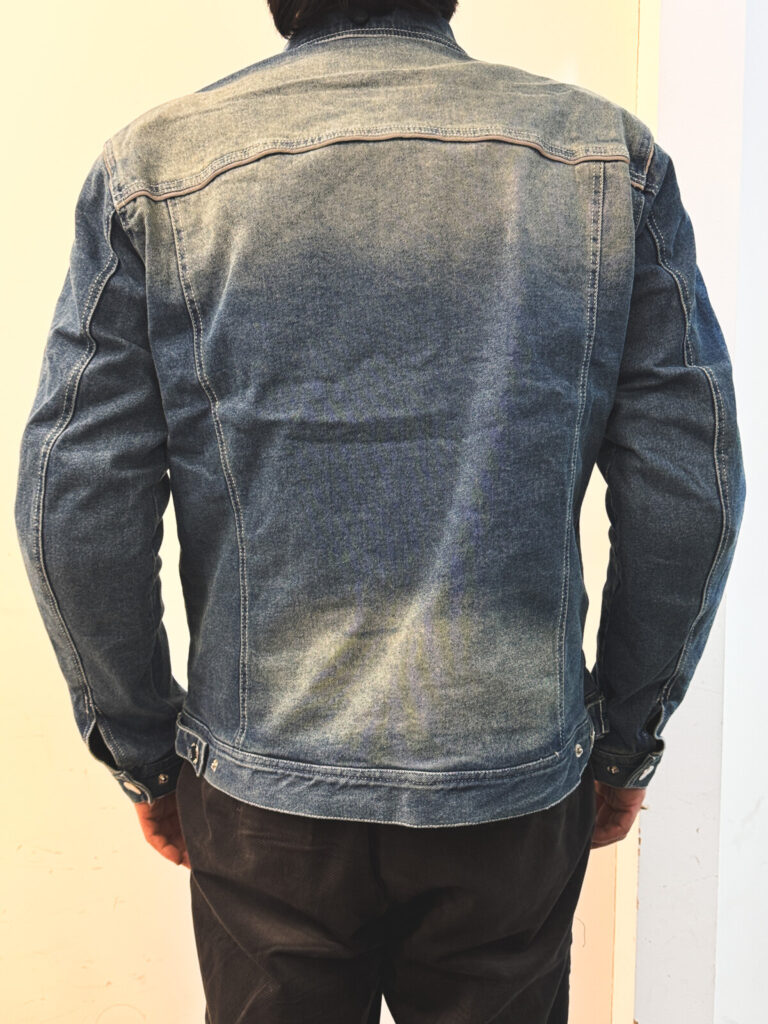 "Back view of a man wearing a heavyweight denim jacket made from a cotton-polyester blend with vintage faded wash"