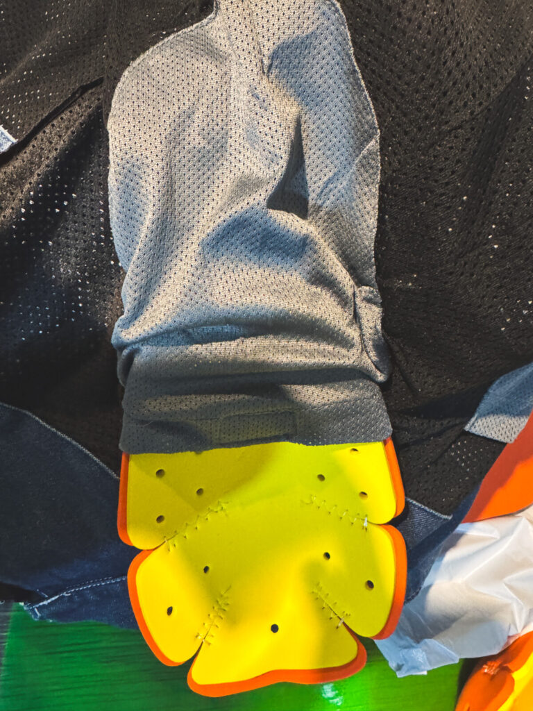 Internal elbow armor partially inserted into mesh-lined sleeve of the denim jacket