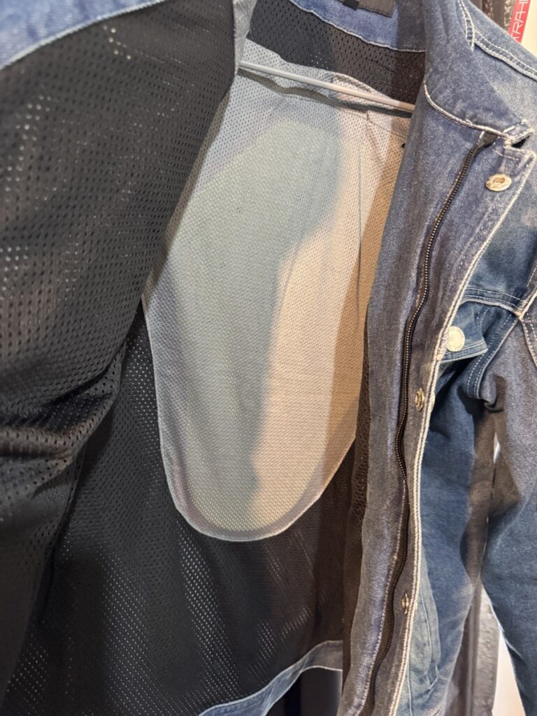 Inside view of a denim jacket showing mesh pocket area for back protector insertion