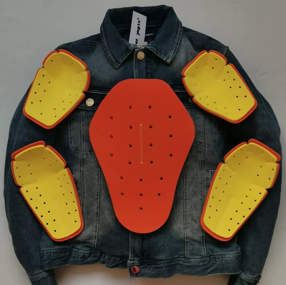 "Motorcycle protective pads arranged on top of a denim jacket to illustrate armor placement for shoulders, elbows, and back"