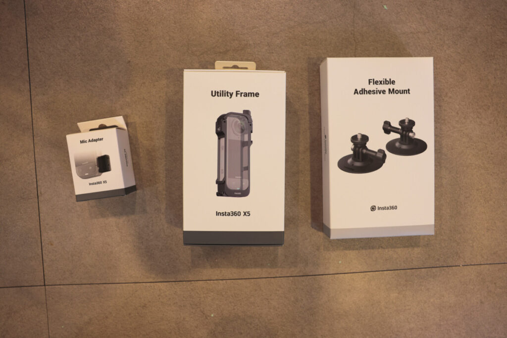 “Insta360 X5 accessories including the Mic Adapter, Utility Frame, and Flexible Adhesive Mount, shown in their retail packaging on a flat surface.”