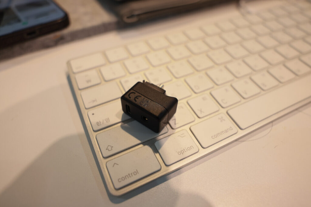 “Close-up shots of a person holding the Insta360 X5 Mic Adapter in different angles, with a keyboard and workspace background.”