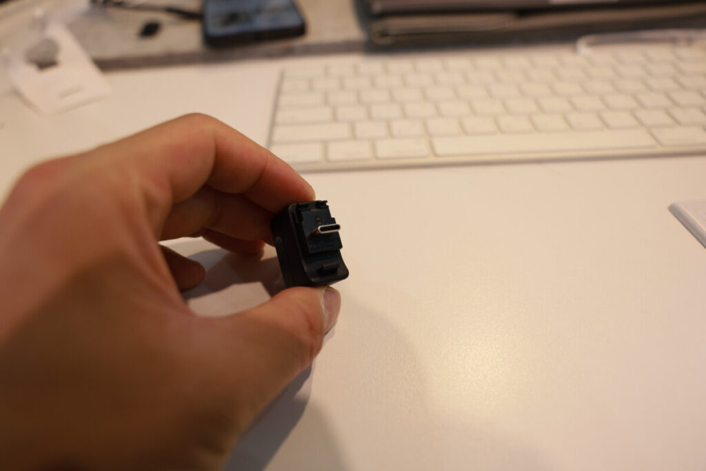 “Close-up shots of a person holding the Insta360 X5 Mic Adapter in different angles, with a keyboard and workspace background.”