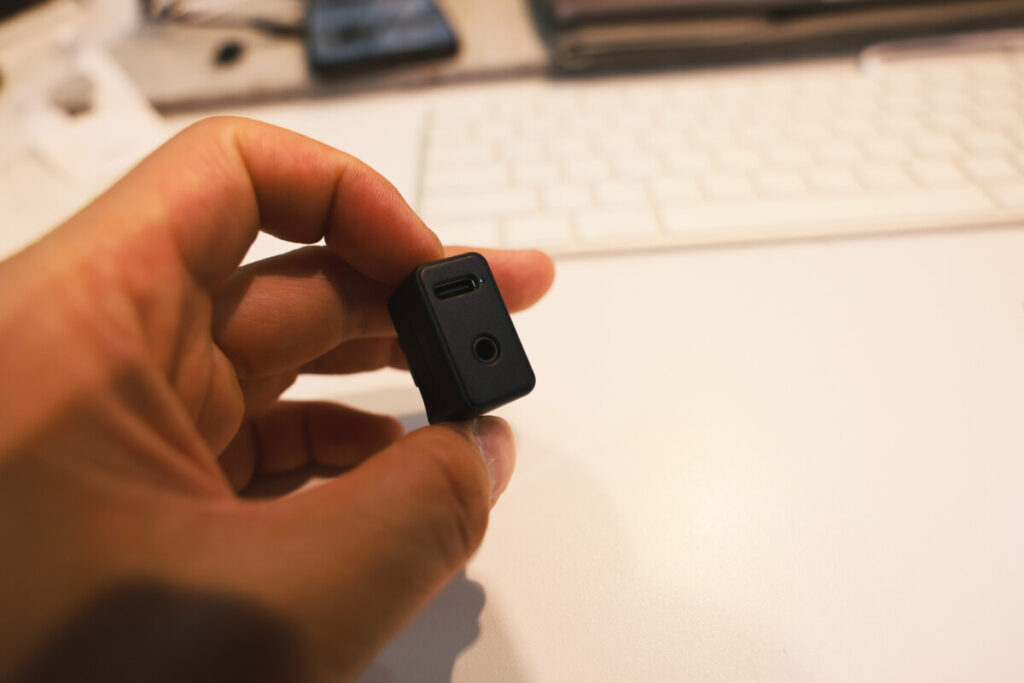 “Close-up shots of a person holding the Insta360 X5 Mic Adapter in different angles, with a keyboard and workspace background.”