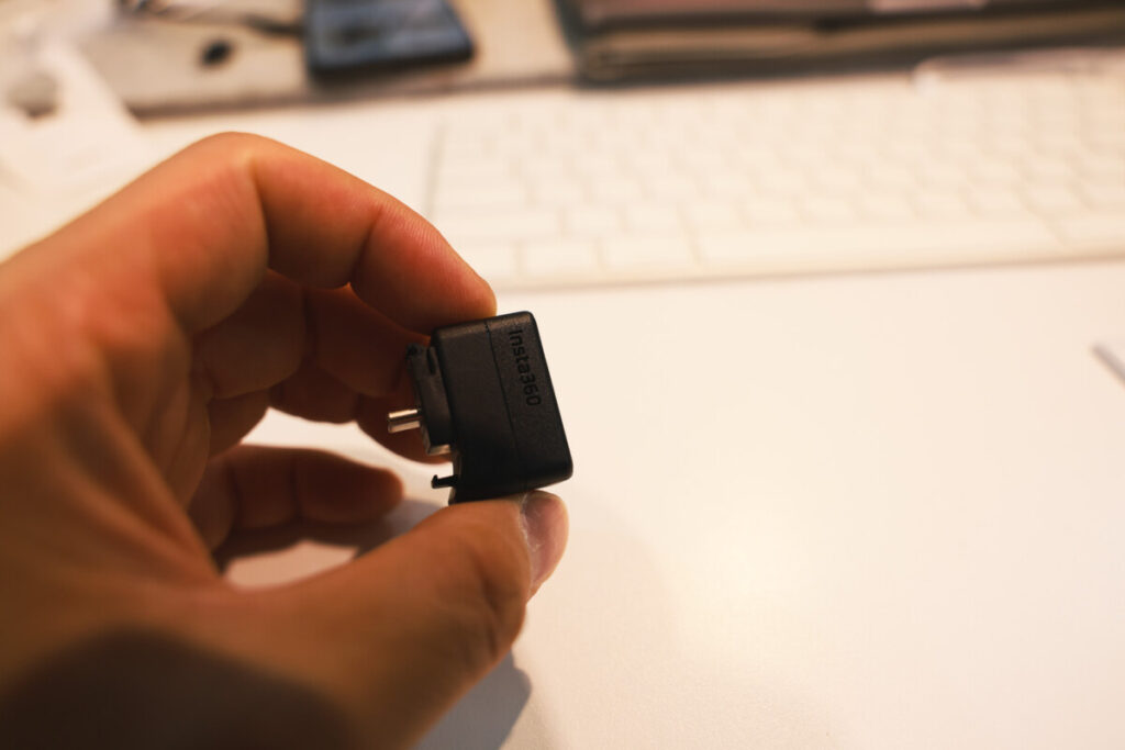 “Close-up shots of a person holding the Insta360 X5 Mic Adapter in different angles, with a keyboard and workspace background.”