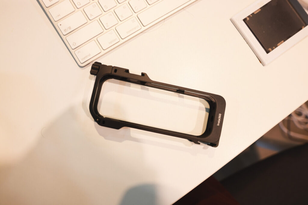 “Top-down view of the Insta360 X5 Utility Frame placed on a white desk next to a keyboard, showcasing its lightweight design and build.”