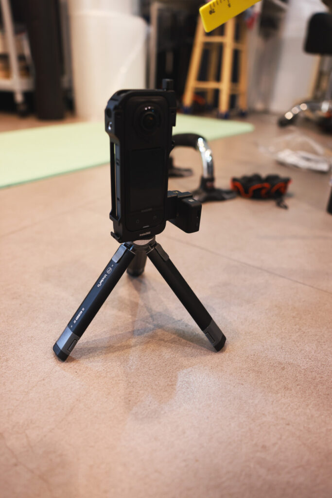 “Three photos showing the Insta360 X5 mounted on a mini tripod with the mic adapter attached, and a side view of the setup with a hand holding the camera.”