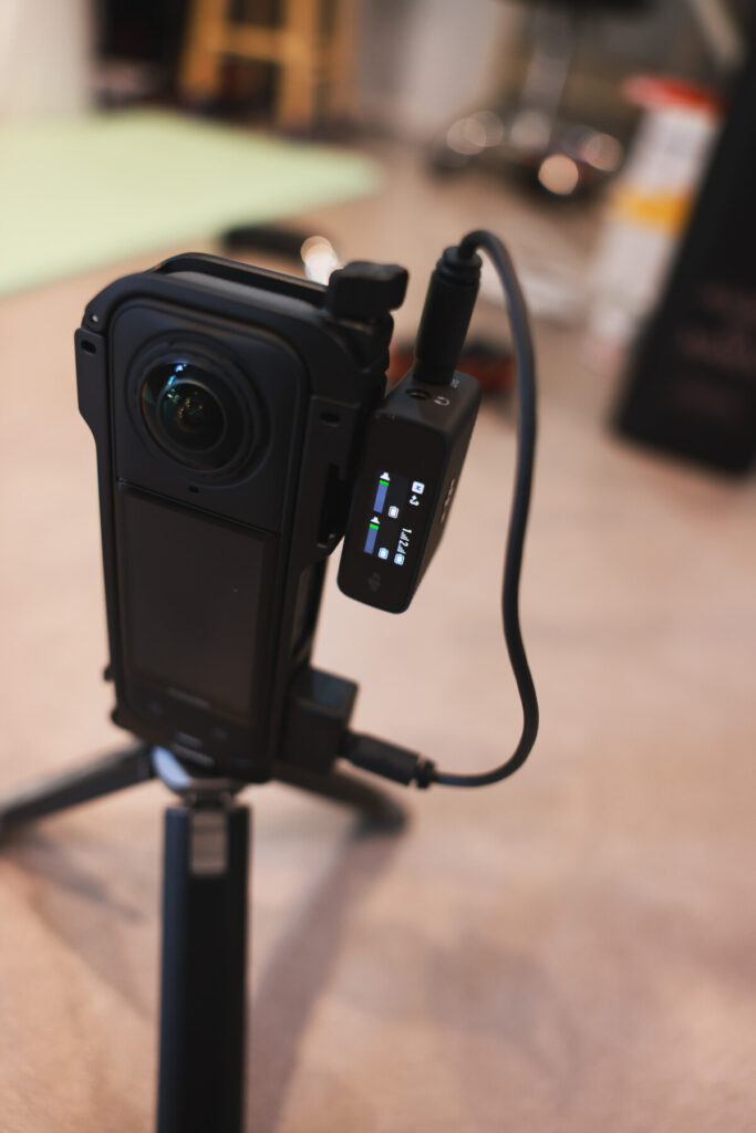 “Insta360 X5 connected to a DJI Mic receiver via 3.5mm cable and mounted on a tripod, shown from multiple angles during indoor setup testing.”