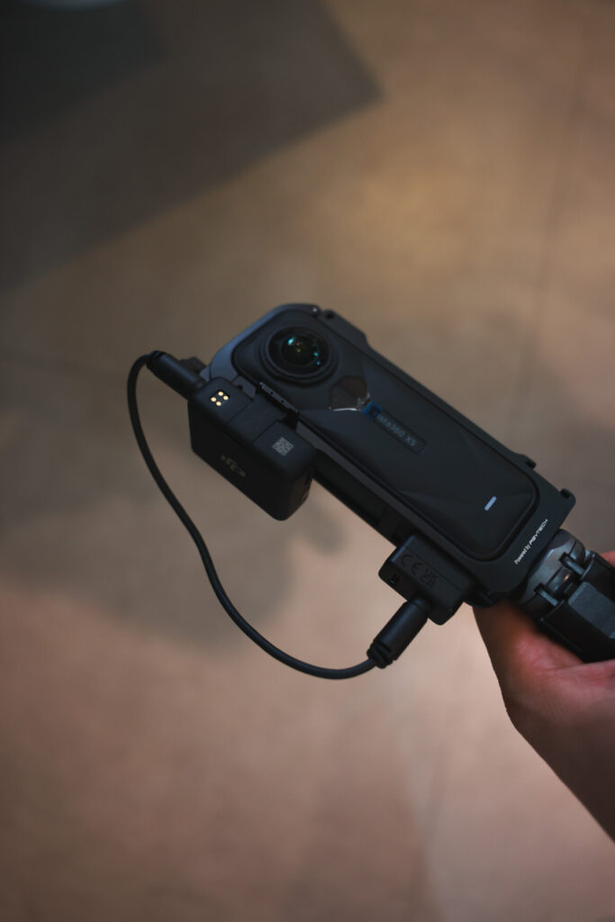 “Insta360 X5 connected to a DJI Mic receiver via 3.5mm cable and mounted on a tripod, shown from multiple angles during indoor setup testing.”