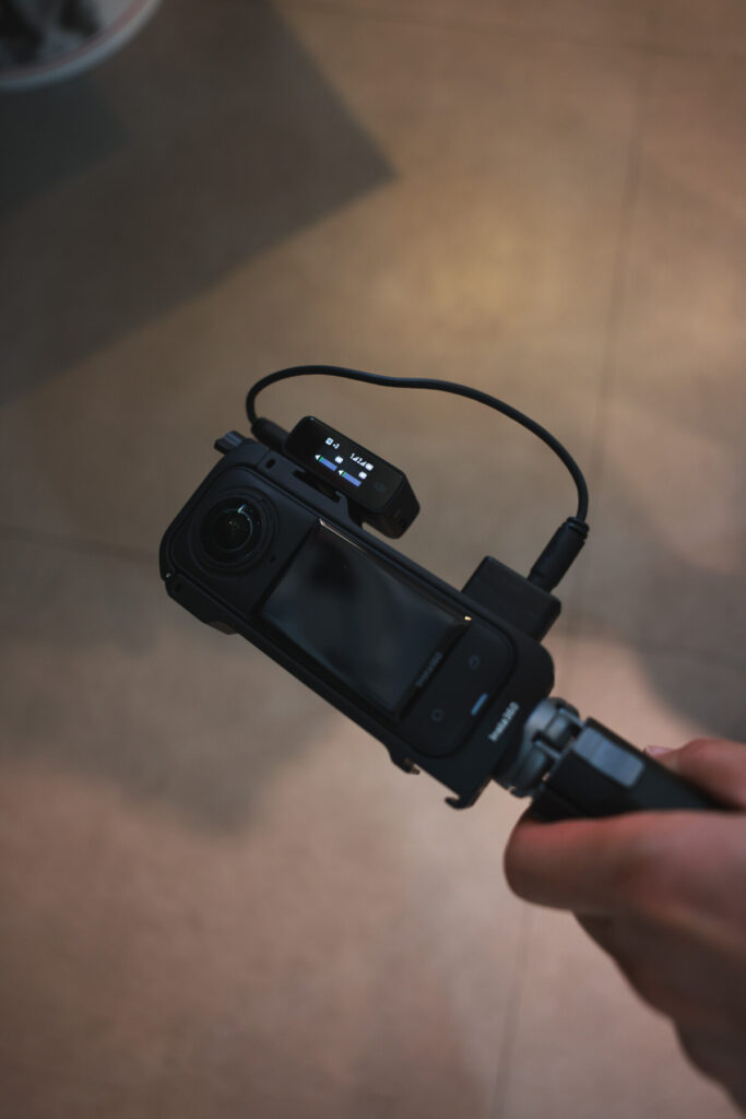 “Insta360 X5 connected to a DJI Mic receiver via 3.5mm cable and mounted on a tripod, shown from multiple angles during indoor setup testing.”