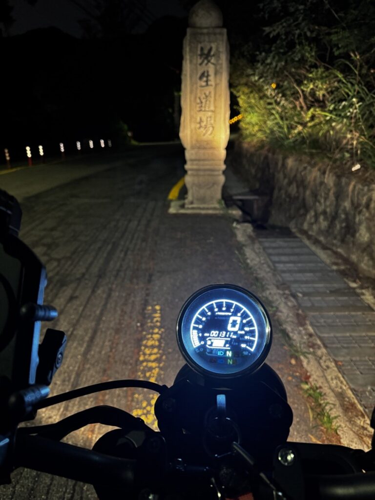 Motorcycle dashboard view in front of the Doseonsa temple road marker at night